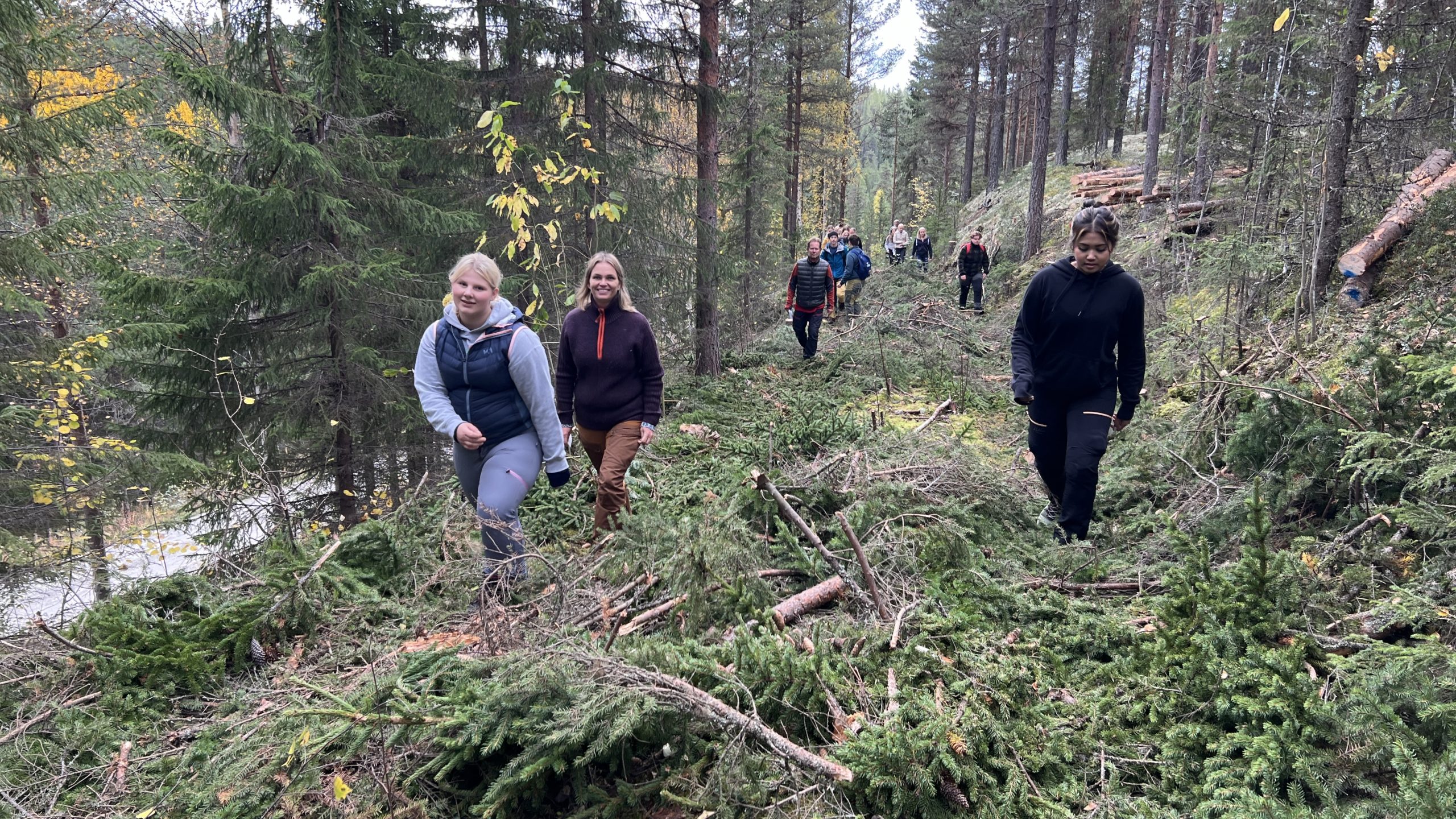 Ungdommer og voksne går på barlagt vei i skogen.