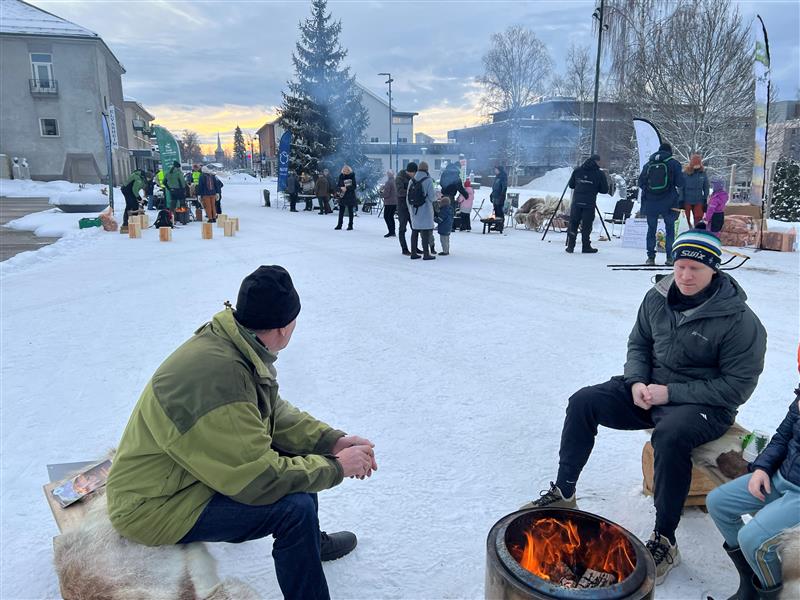 To menn ved bålpanne og ulike stands i bakgrunnen.